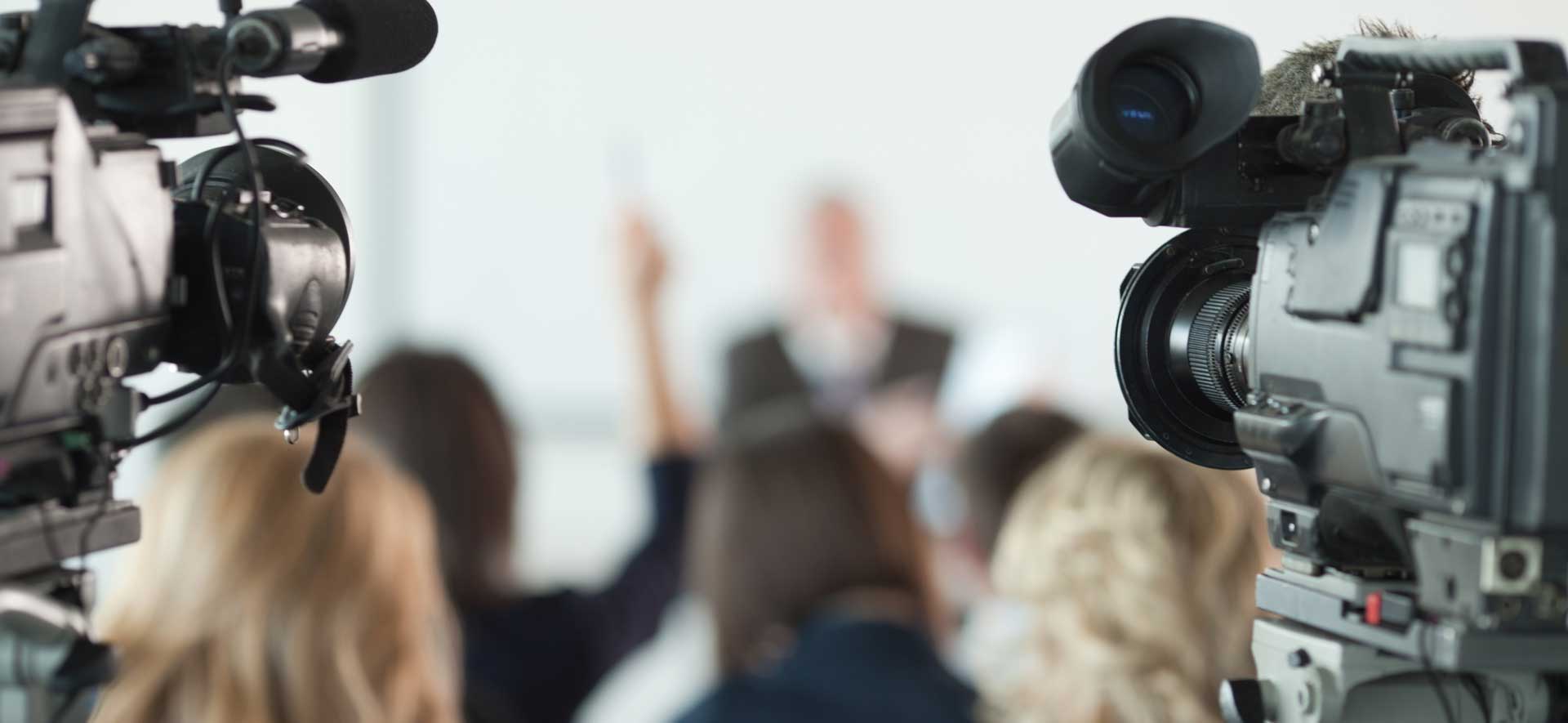 Cameras pointed at a speaking individual at a press conference