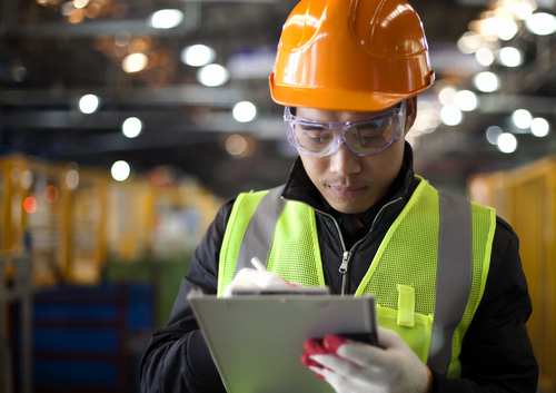 A worker wearing a hardhat conducts safety checks