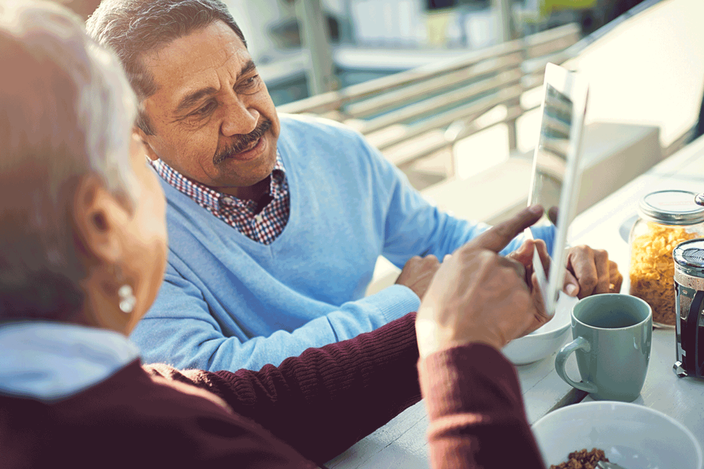 A pair of retirees look over an ipad with information about their pensions.